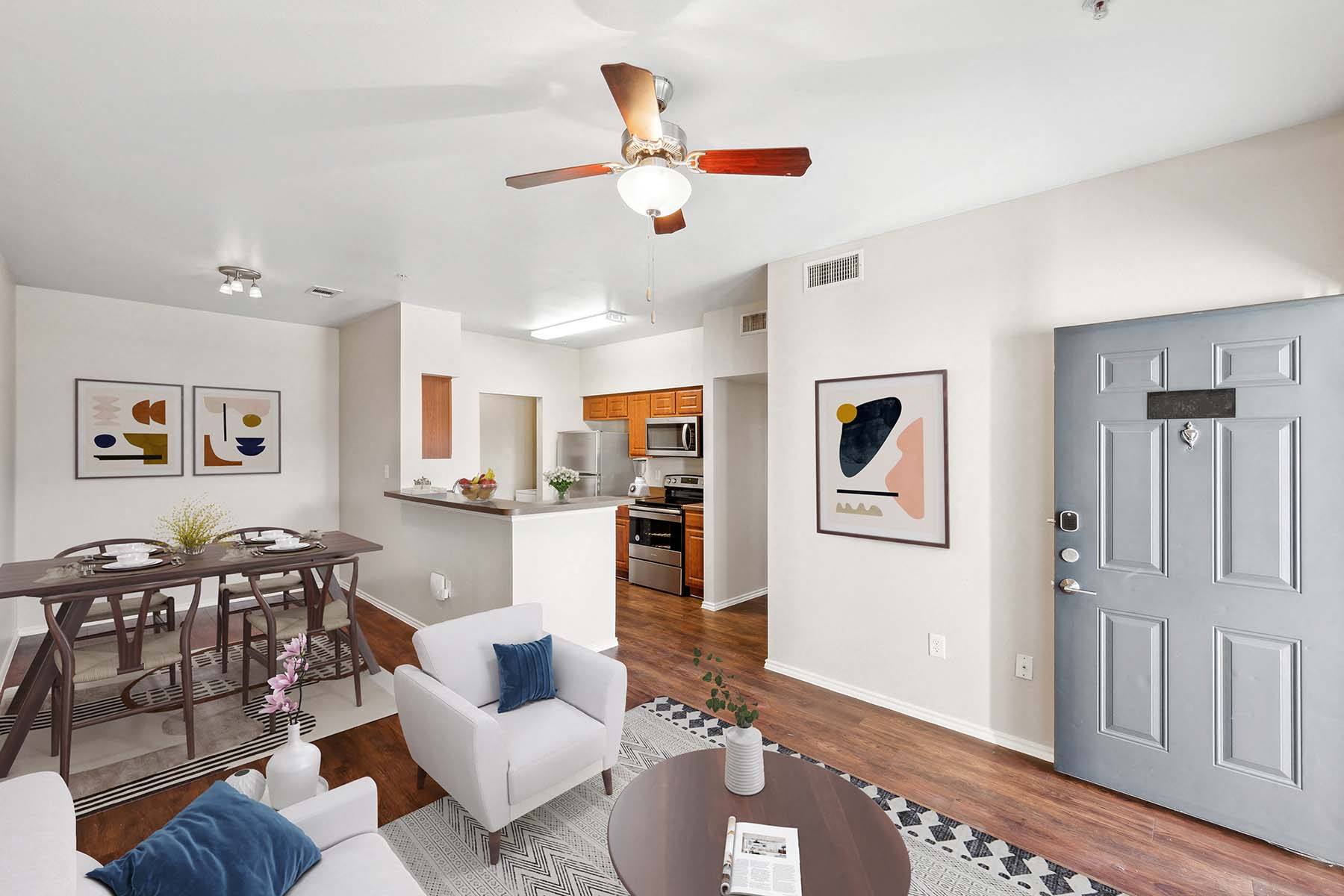 an open living room and kitchen with a table and a ceiling fan